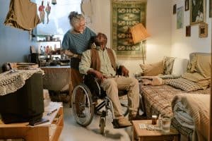 Caregiver assisting senior man in wheelchair in cozy living room.